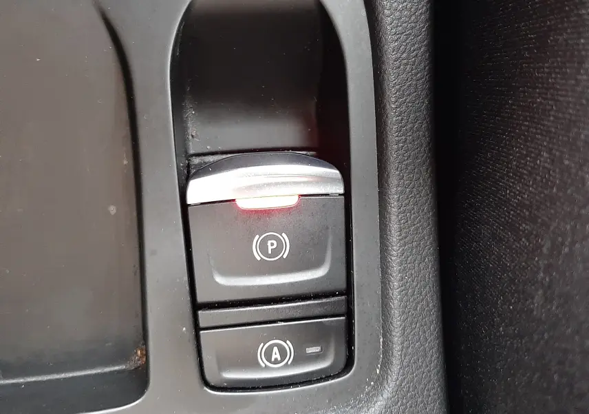 Gros plan sur les commandes de frein à main électrique et d'assistance au démarrage du Renault Clio V rouge flamme.