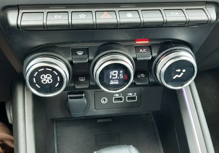 Vue rapprochée de la console centrale de la Renault Clio V hybride, montrant les commandes de climatisation et ports USB.
