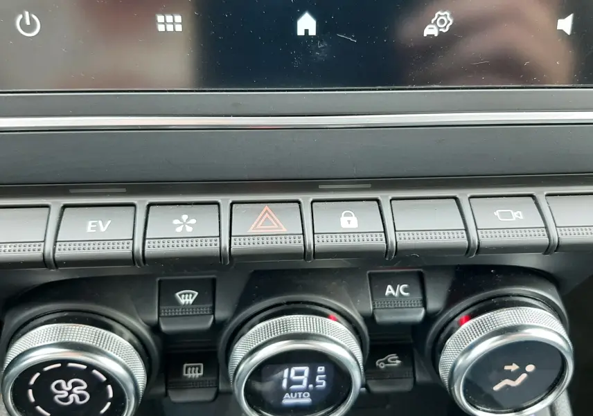 Détail du tableau de bord de la Renault Clio V hybride, boutons de climatisation et écran tactile en vue rapprochée.
