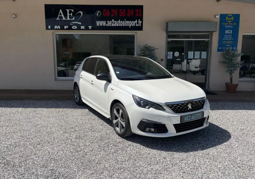 Peugeot 308 GT-Line blanche vue en 3/4 avant droit, avec jantes alliage et calandre noire distinctive.