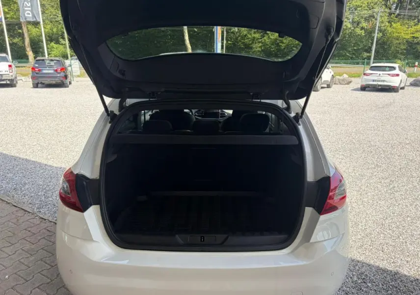 Vue arrière d'une Peugeot 308 GT-Line blanche de 2017 avec le coffre ouvert, montrant l'espace de chargement vide.