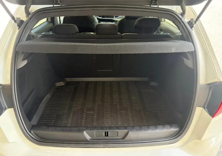 Coffre ouvert d'une Peugeot 308 GT-Line blanche de 2017, vue arrière montrant l'espace de chargement et la tablette cache-bagages.