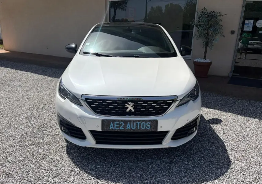 Vue frontale d’une Peugeot 308 GT-Line blanche de 2017, avec calandre noire et logo lion distinctif.