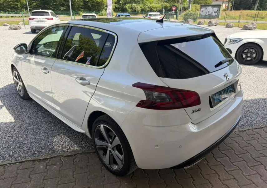 Peugeot 308 GT-Line blanc vue 3/4 arrière droit, avec jantes alliage et vitres arrière teintées.