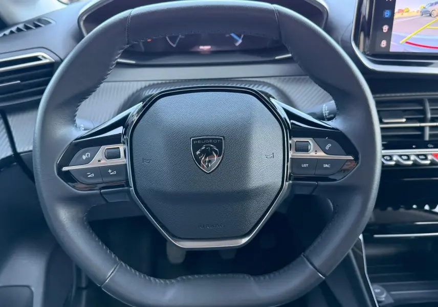 Vue rapprochée du volant cuir noir du Peugeot 208 2025 avec commandes intégrées et tableau de bord numérique partiel.