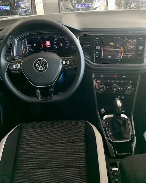 Vue intérieure du Volkswagen T-Roc 2021 montrant le volant noir, tableau de bord digital et écran central avec navigation.