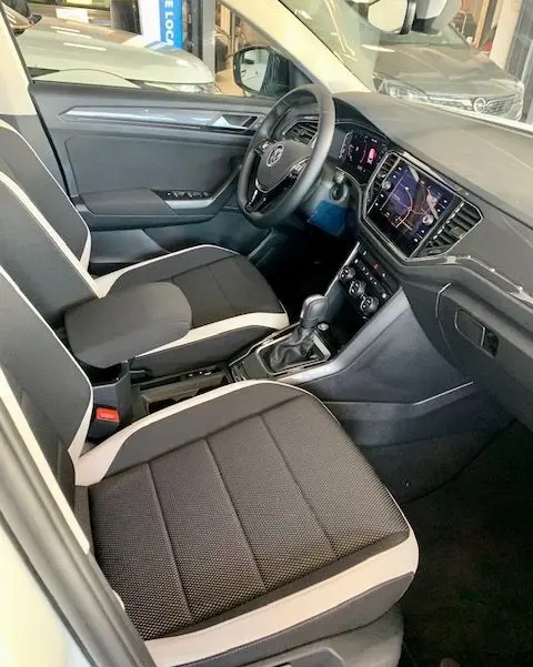 Vue intérieure côté conducteur du Volkswagen T-Roc 2021, sièges noir et beige, tableau de bord avec écran tactile et volant multifonction.