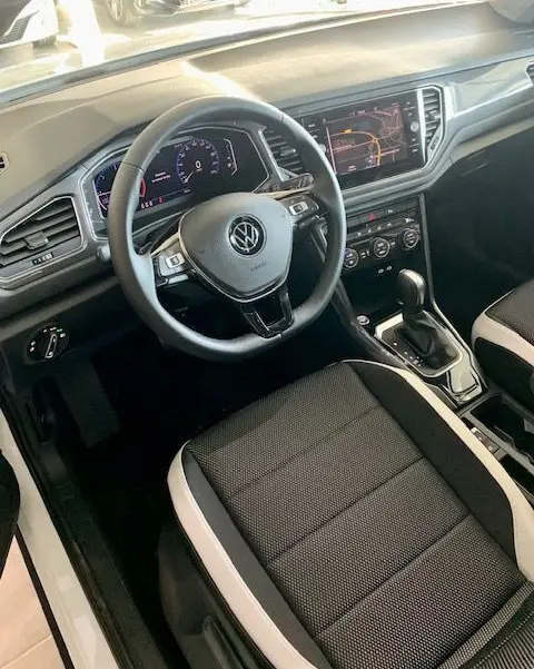 Vue intérieure côté conducteur du Volkswagen T-Roc 2021, tableau de bord numérique et sellerie noire avec surpiqûres claires.