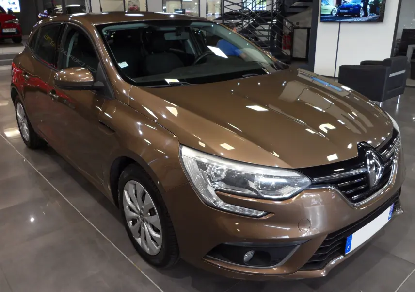 Renault Mégane IV TCe 100 Life brun capuccino vue 3/4 avant en intérieur avec phares et calandre distinctifs.