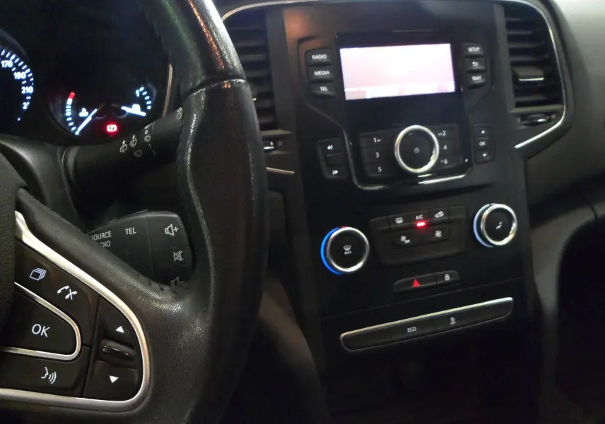 Intérieur de la Renault Mégane IV TCe 100 Life 2016, vue centrée sur le tableau de bord et le volant noir avec commandes intégrées.