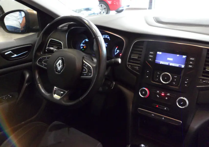 Intérieur de la Renault Mégane IV TCe 100 Life 2016, vue côté conducteur sur le volant et la console centrale noire.