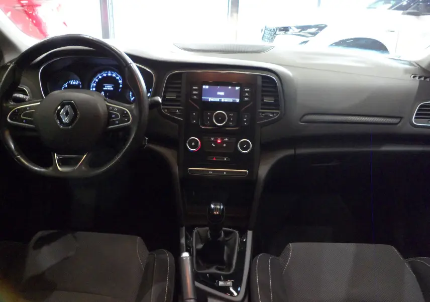 Vue intérieure avant de la Renault Mégane IV TCe 100 Life 2016, tableau de bord noir avec console centrale et volant multifonctions.