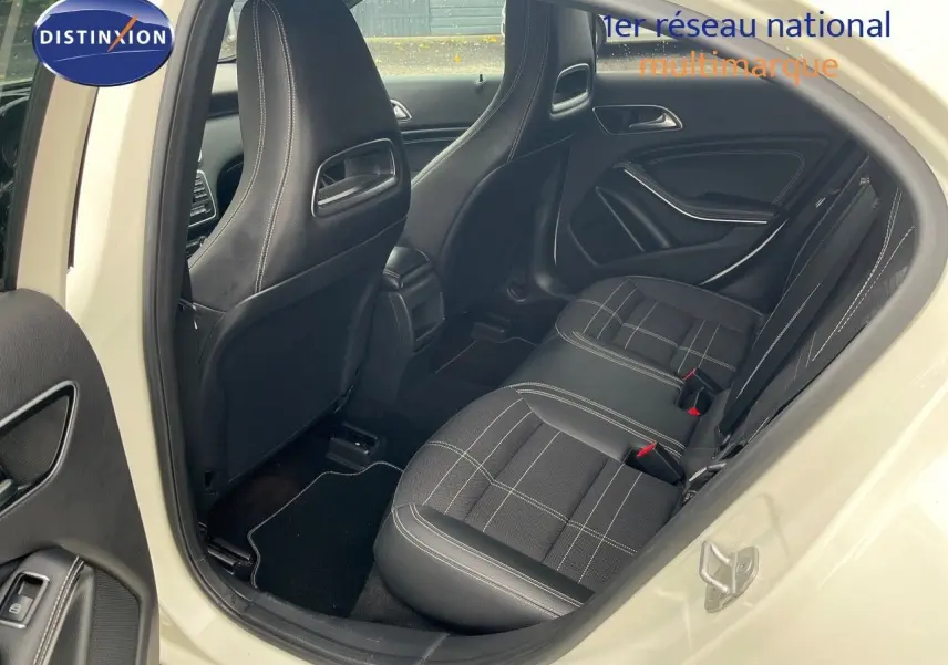 Vue intérieure arrière côté droit d'une Mercedes Classe A 180 Sensation blanche de 2013 avec sièges tissu noir à surpiqûres blanches.