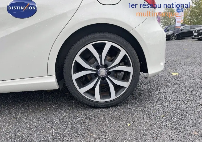 Gros plan sur la roue arrière droite d'une Mercedes Classe A 180 Sensation blanche de 2013, avec jante alliage distinctive.