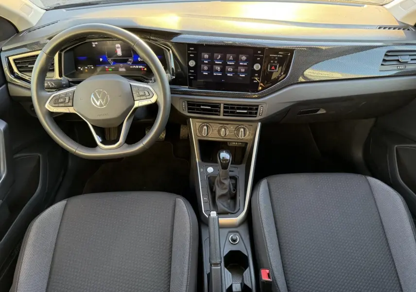 Vue intérieure avant du Volkswagen Taigo 2025, tableau de bord noir avec écran tactile et volant multifonction.