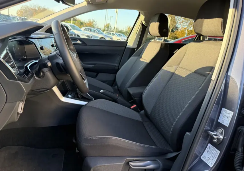 Vue intérieure côté conducteur du Volkswagen Taigo 2025 gris INC, montrant sièges avant et tableau de bord moderne.