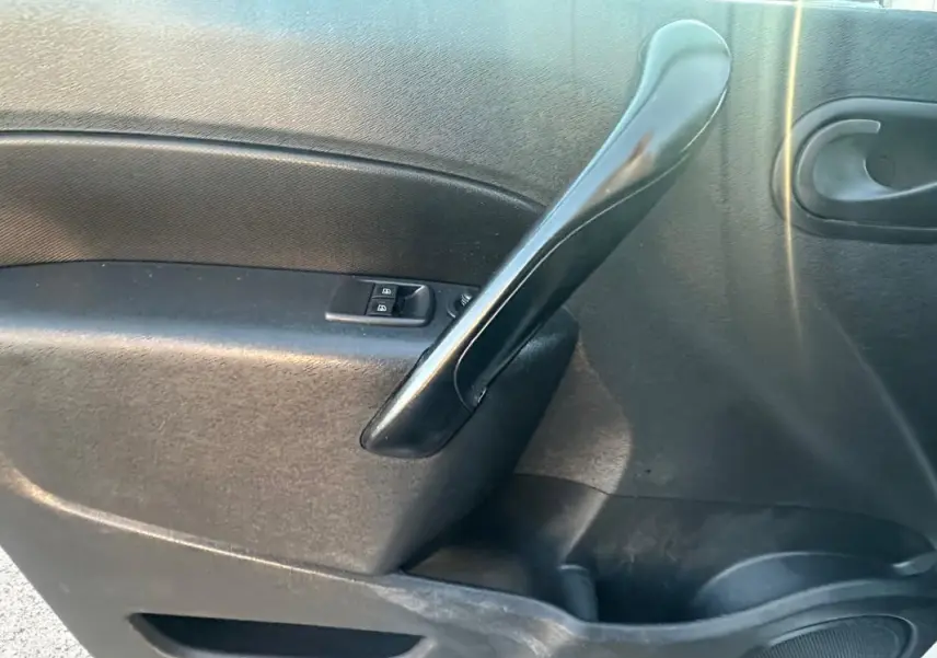 Gros plan sur la poignée intérieure noire de la porte côté gauche du Renault Kangoo Express blanc 2020.