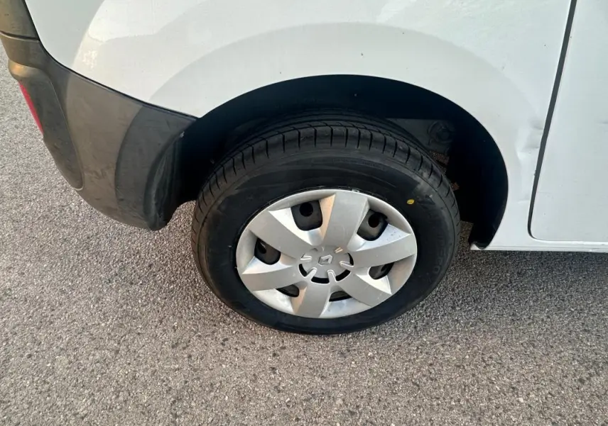 Gros plan sur la roue arrière droite d'un Renault Kangoo Express blanc avec enjoliveur et pare-chocs noir.