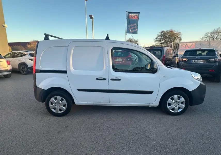 Renault Kangoo Express blanc vu de profil côté gauche, fourgonnette utilitaire avec porte latérale et barres de toit.