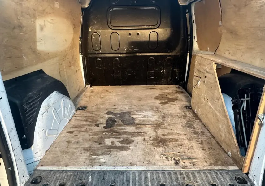 Vue intérieure arrière du Renault Kangoo Express blanc 2020, montrant la zone de chargement en bois usé et les parois latérales.