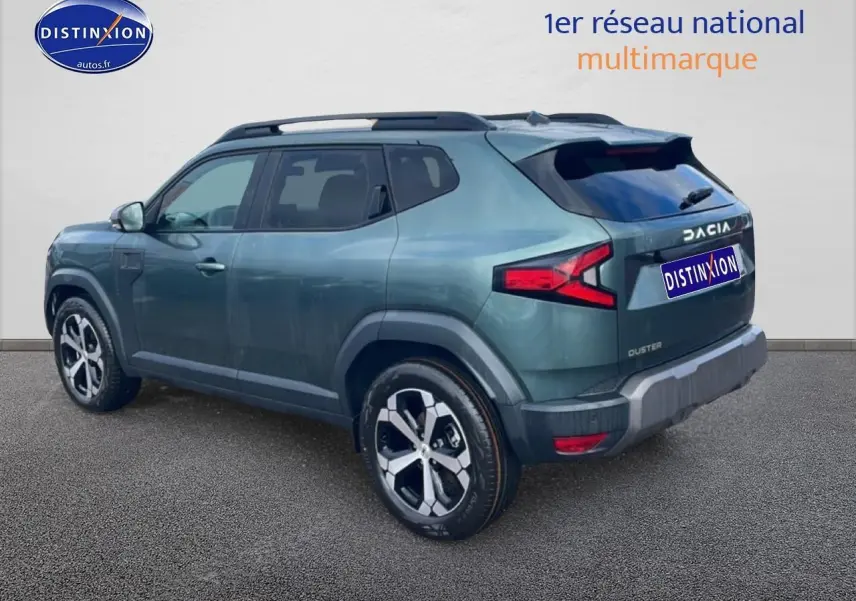 Vue 3/4 arrière droite du Dacia Duster 2026 vert cèdre avec barres de toit et jantes alu distinctives.