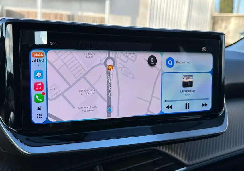 Écran tactile du tableau de bord de la Peugeot 208 blanc, affichant navigation et musique en intérieur.