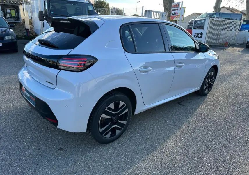 Peugeot 208 Hybrid blanc vue 3/4 arrière droit, jantes alliage noires et feux arrière LED distinctifs.