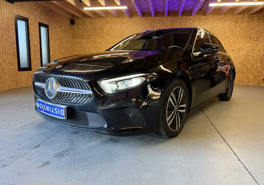 Mercedes Classe A noire vue en 3/4 avant droit dans un garage avec jantes alliage et calandre étoilée chromée.