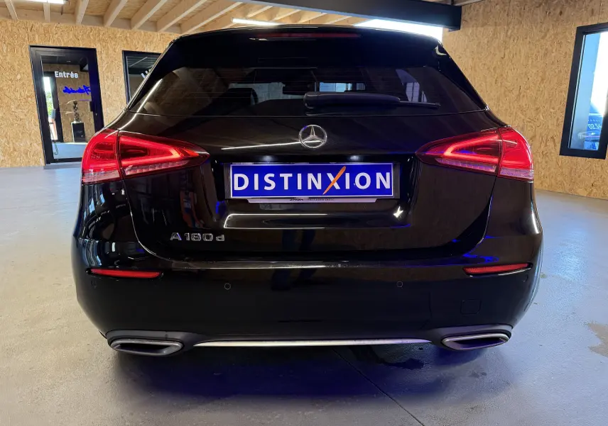 Vue arrière d'une Mercedes Classe A noire avec feux LED et double sortie d'échappement chromée en intérieur showroom.