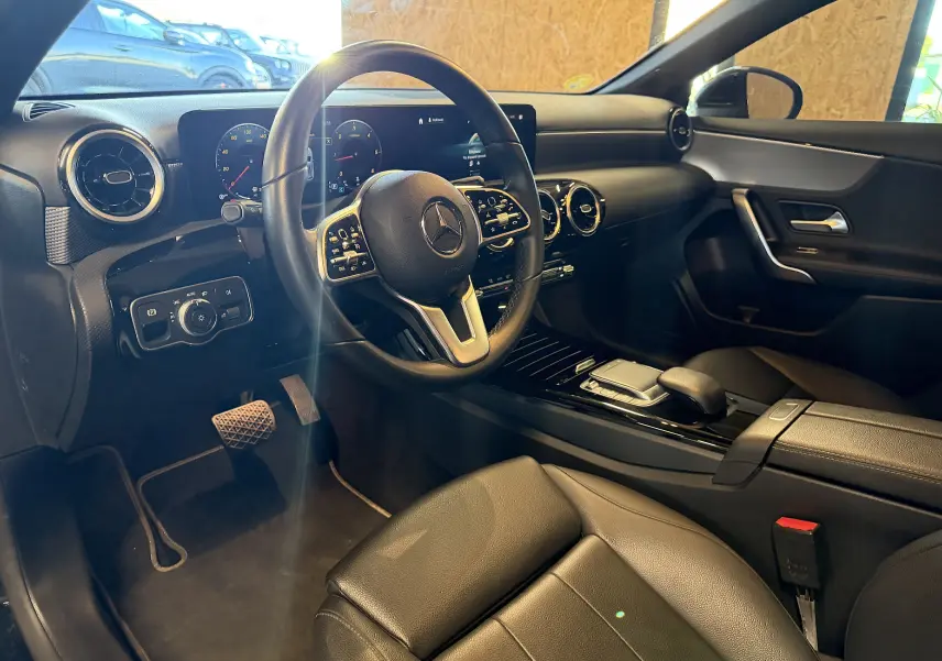 Intérieur noir de la Mercedes Classe A 2022 vu côté conducteur, volant cuir multifonctions et tableau de bord numérique.
