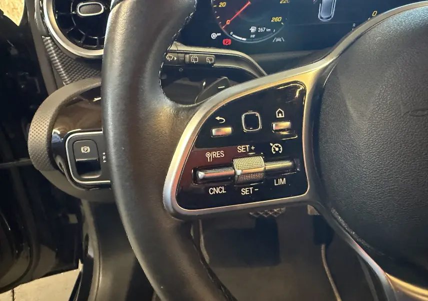 Gros plan sur le volant cuir multifonctions noir de la Mercedes Classe A 2022, avec commandes de régulateur de vitesse.