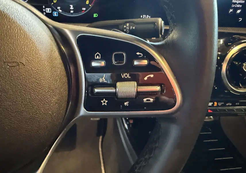 Gros plan sur les commandes multifonctions côté gauche du volant cuir noir d’une Mercedes Classe A 2022.