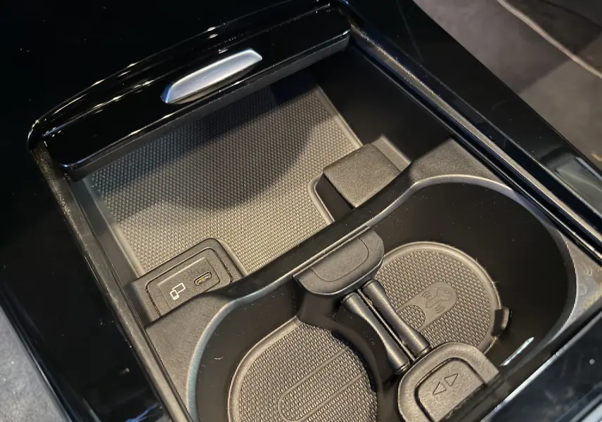 Gros plan sur la console centrale noire de la Mercedes Classe A 2022, avec porte-gobelets et prise USB visible.