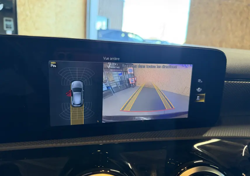 Écran tactile intérieur montrant la caméra de recul et l’aide au stationnement d’une Mercedes Classe A noire.