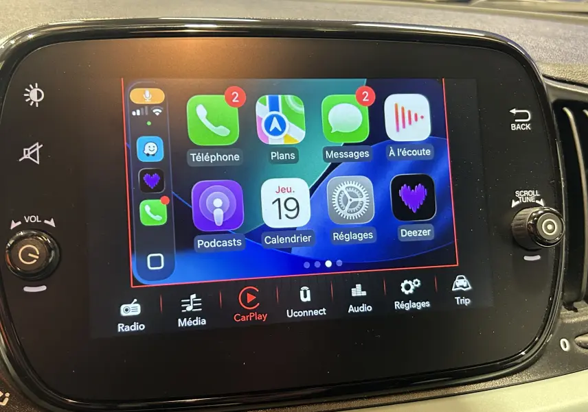 Écran tactile central de la Fiat 500 2023 affichant l'interface Apple CarPlay avec plusieurs applications visibles.