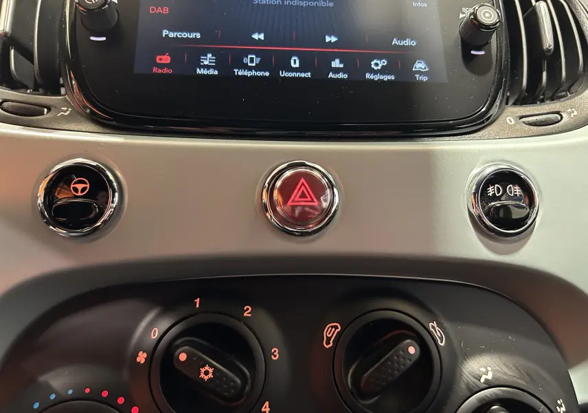 Détail du tableau de bord de la Fiat 500 2023 avec commandes climatisation et écran tactile affichant le menu radio.