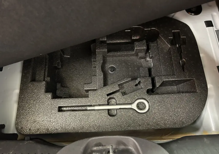 Gros plan sur le coffre à outils noir avec une clé d'attelage métallique dans une FIAT 500 70 Hybride Pack Confort & Style 2023.