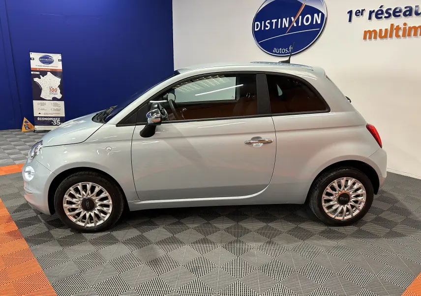 Vue de profil droit d'une FIAT 500 2023 Rugiada Green aux jantes multibranches, dans un showroom intérieur.