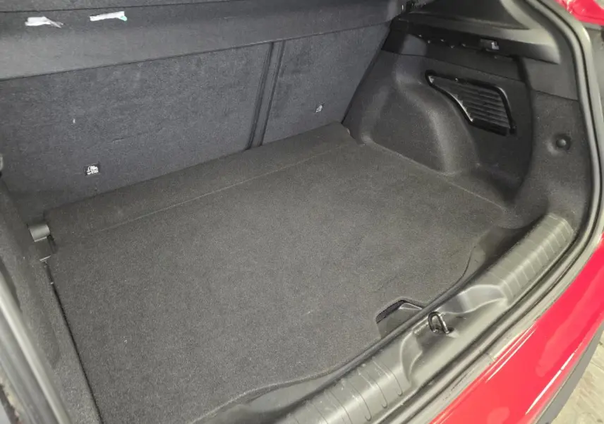 Vue du coffre ouvert de la FIAT 600 Hybrid rouge 2024, montrant l'espace de rangement intérieur noir.