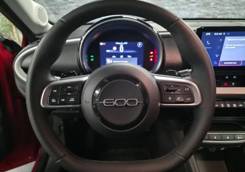 Vue frontale du volant noir de la FIAT 600 2024 avec combiné numérique et écran tactile central.