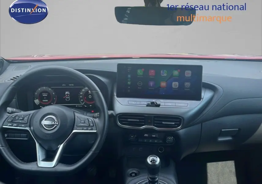 Vue intérieure du tableau de bord du Nissan Juke rouge Fuji Metal 2024, avec volant multifonction et écran tactile central.