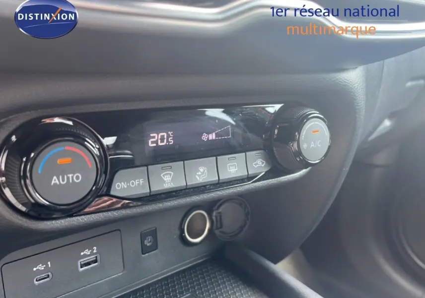 Détail de la console centrale du Nissan Juke 2024 rouge Fuji Metal, montrant les commandes de climatisation et ports USB.