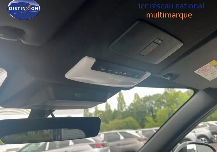 Vue intérieure du toit et rétroviseur d’un Nissan Juke rouge Fuji Metal 2024, avec commandes au plafond visibles.