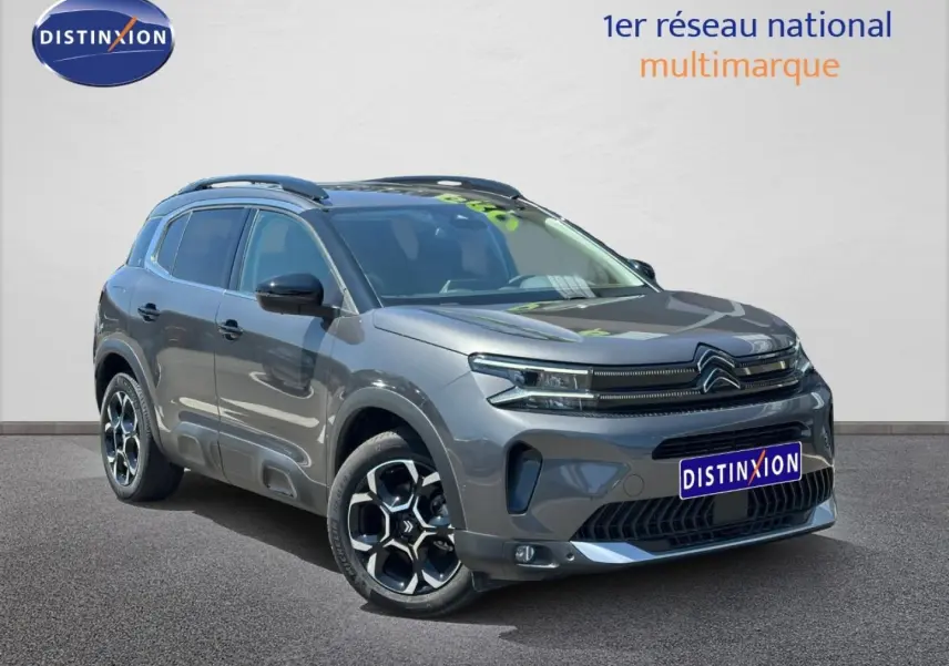 Citroën C5 Aircross gris Platinium en 3/4 avant droit avec jantes alu et barres de toit visibles.