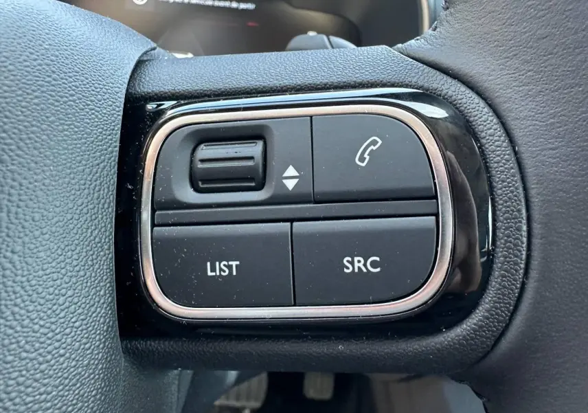 Gros plan sur les commandes noires et argentées du volant cuir du Citroën C5 Aircross Gris Platinium 2025.