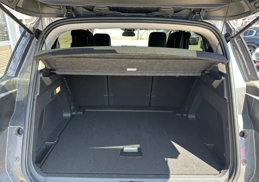 Coffre ouvert vu de l'arrière d'un Citroën C5 Aircross gris Platinium avec cache-bagages relevé.