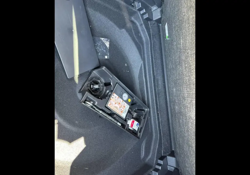 Vue du coffre du Citroën C5 Aircross 2025 gris Platinium, montrant le compartiment de rangement avec kit de réparation pneus.