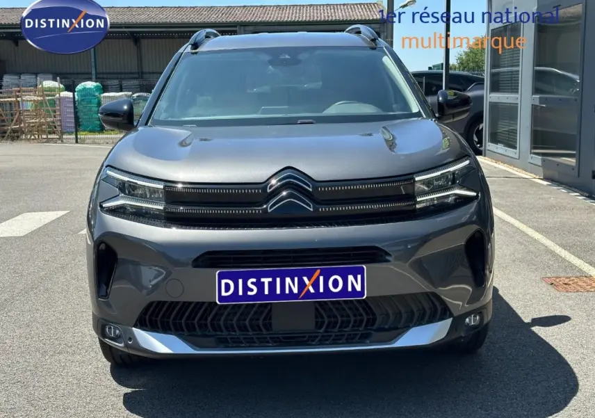 Vue avant d'un Citroën C5 Aircross gris Platinium avec calandre distinctive et barres de toit visibles.