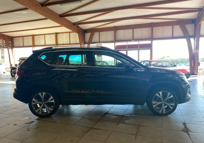 Profil côté gauche d'un SUV SEAT Ateca Urban noir 2019 avec jantes alliage et toit ouvrant en intérieur lumineux.