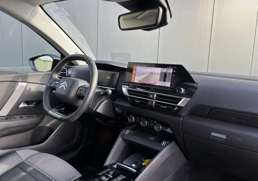 Vue intérieure avant droite de la Citroën C4 2024, tableau de bord noir avec écran tactile affichant la caméra de recul.